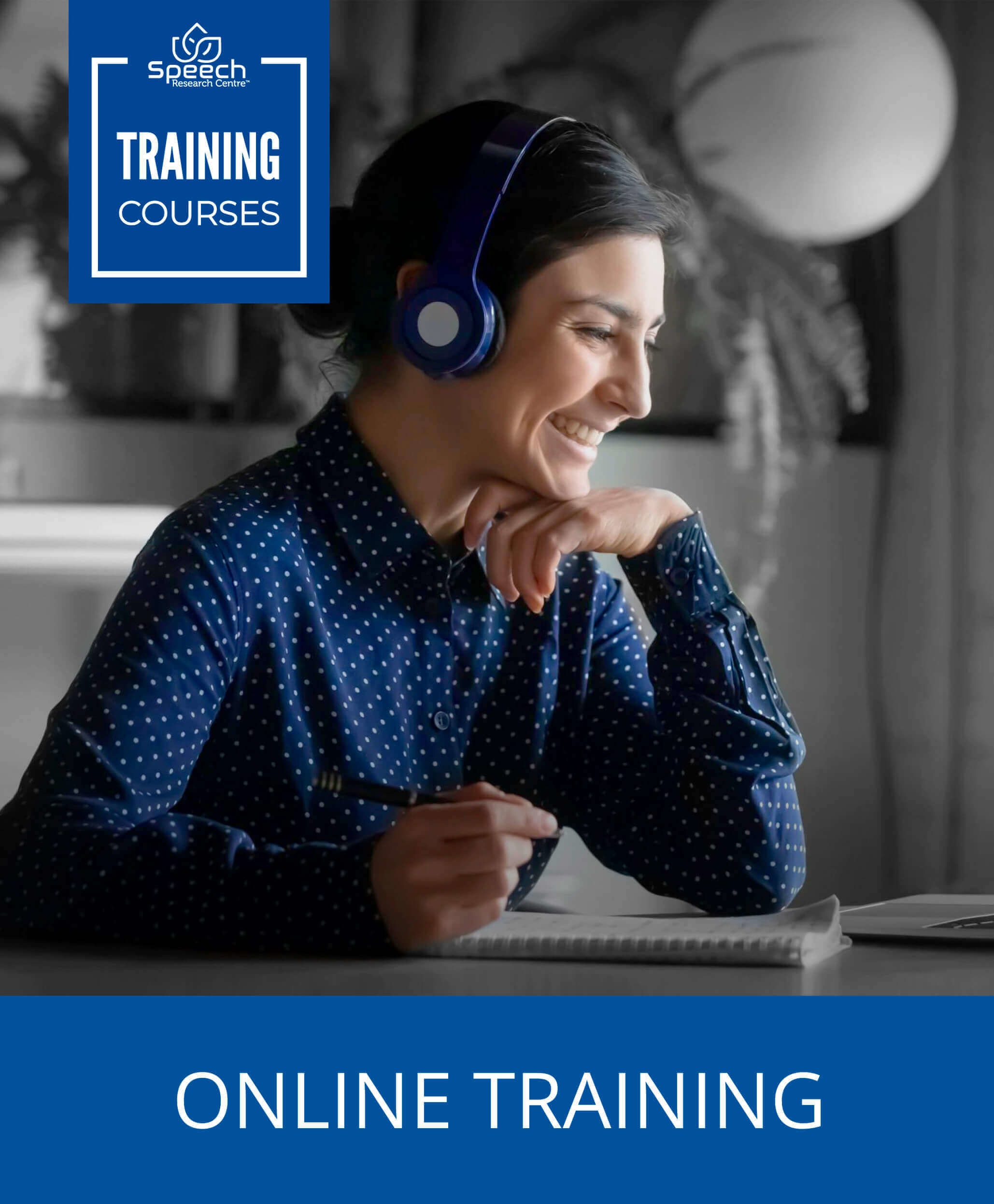 smiling woman with headphones over her head taking notes with a pen and paper